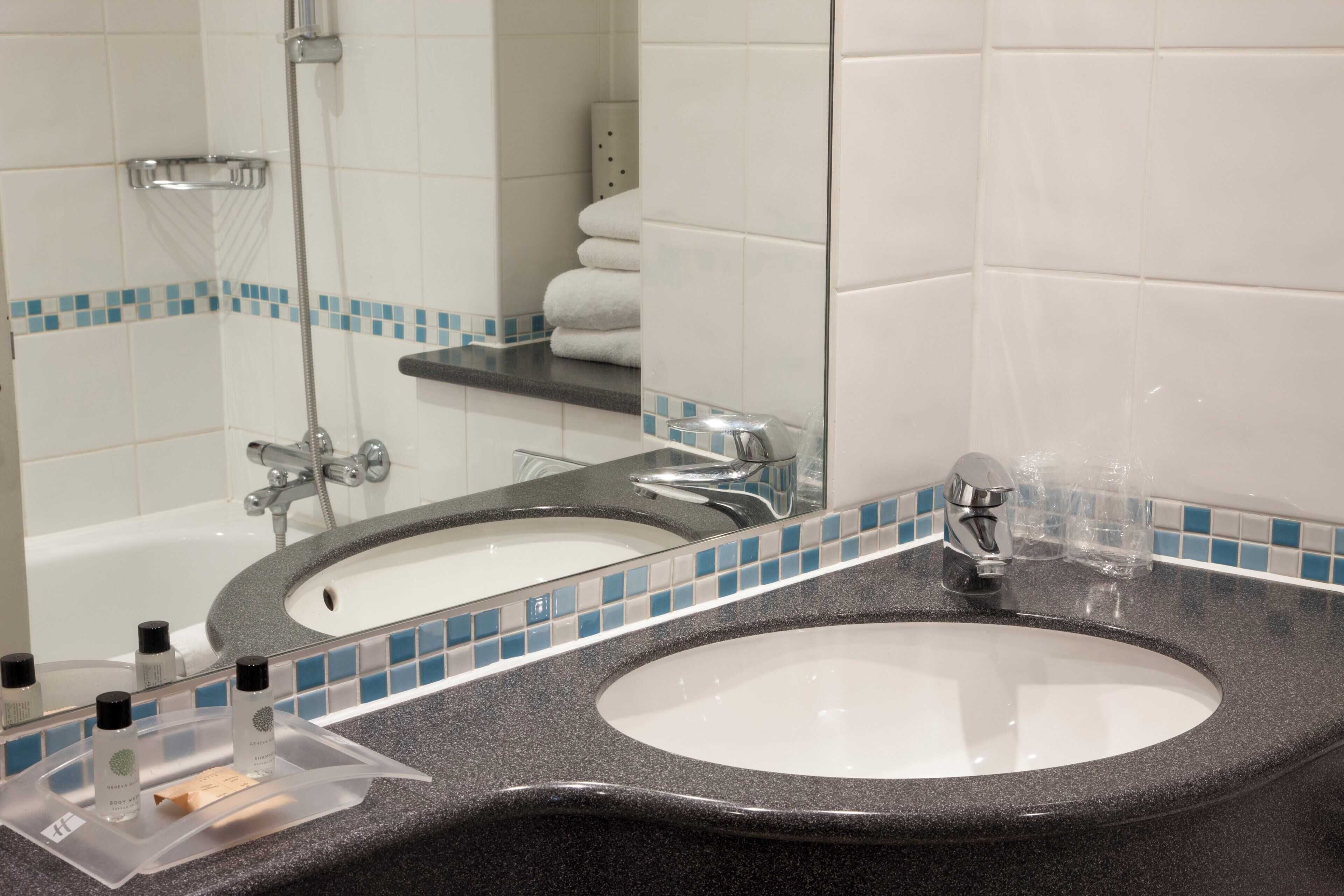 A bathroom with a double sink, a shower, and a towel rack.