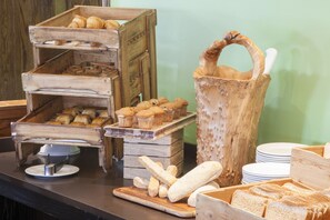 A buffet setup with wooden serving trays and a rustic wooden bucket with a handle. - Holiday Inn Norwich by IHG (Norwich)
