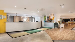 A hotel reception area with a counter, a seating area, and a dining space. - Holiday Inn Norwich by IHG (Norwich)