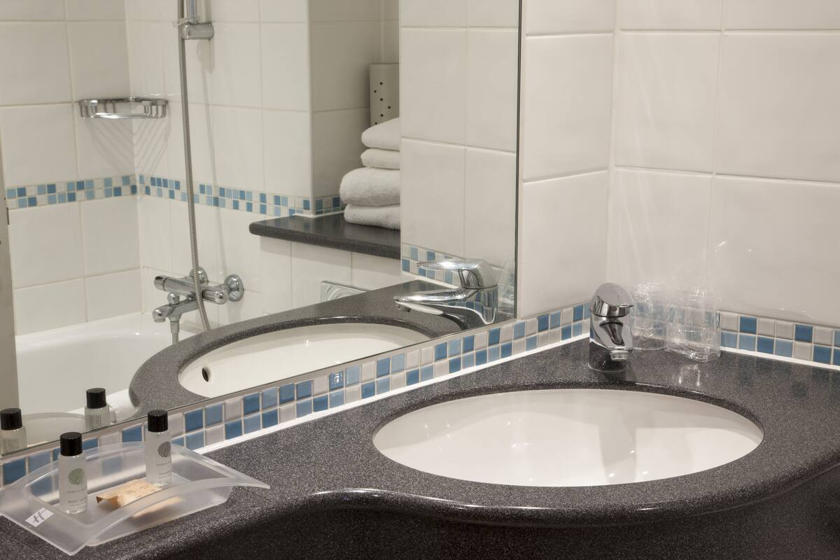 A bathroom with two sinks, a shower, and a towel rack.