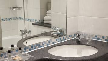 A bathroom with two sinks, a shower, and a towel rack.