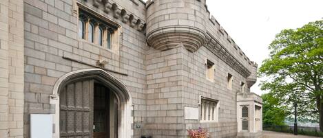 A historic building with a large arched entrance, a turret, and a stone facade.