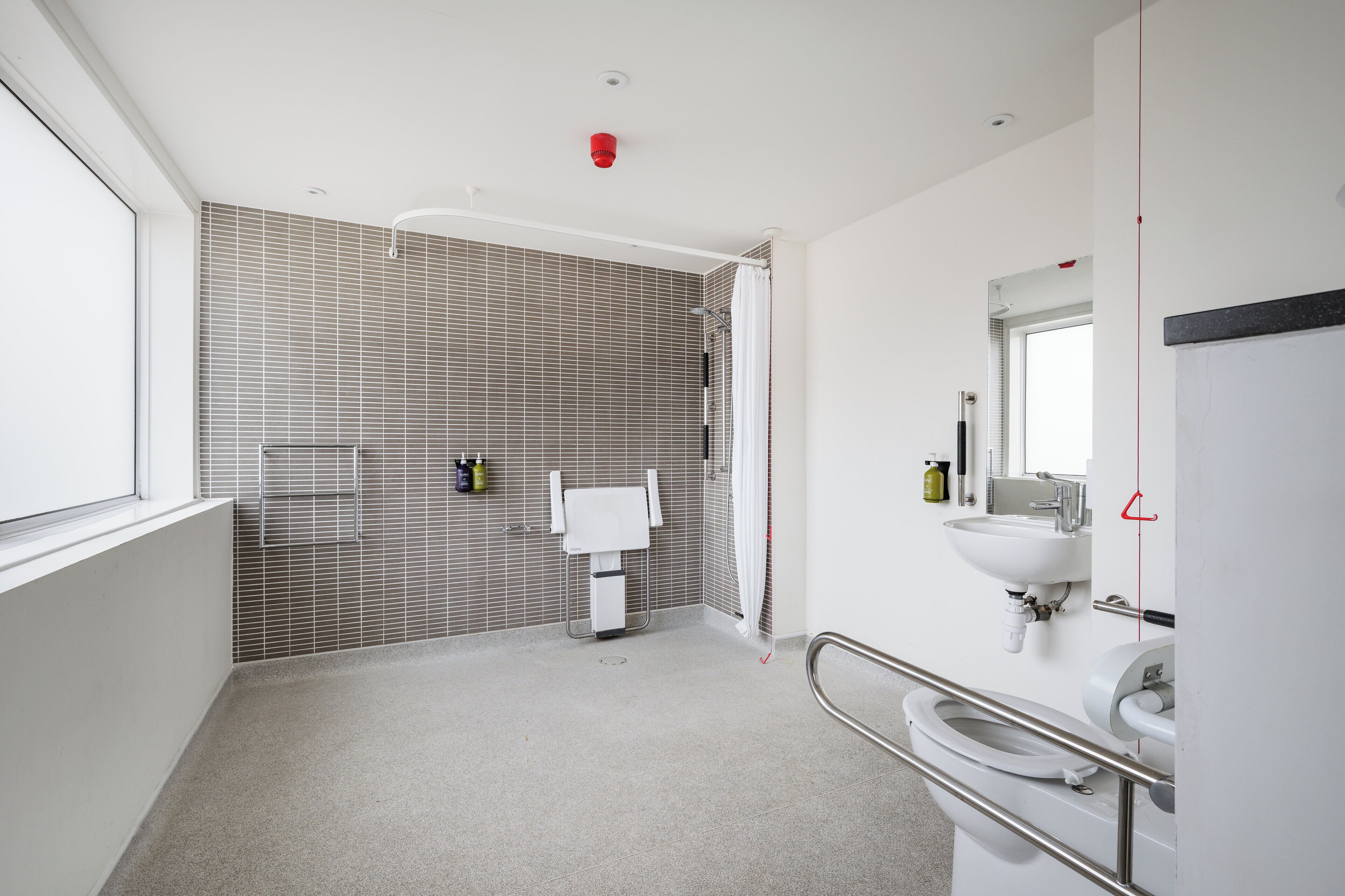 A modern bathroom with a shower, toilet, and sink.