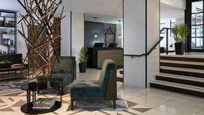 Un vestíbulo moderno con mostrador de recepción, una escalera y zonas de estar.