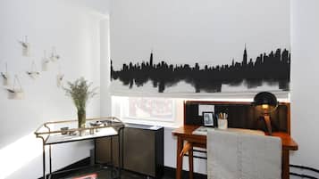 A modern office space with a city skyline mural, a radiator, a desk with a chair, and a glass shelving unit.