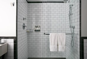 A modern shower with white tiles, a towel rack, and a glass-enclosed shower area.