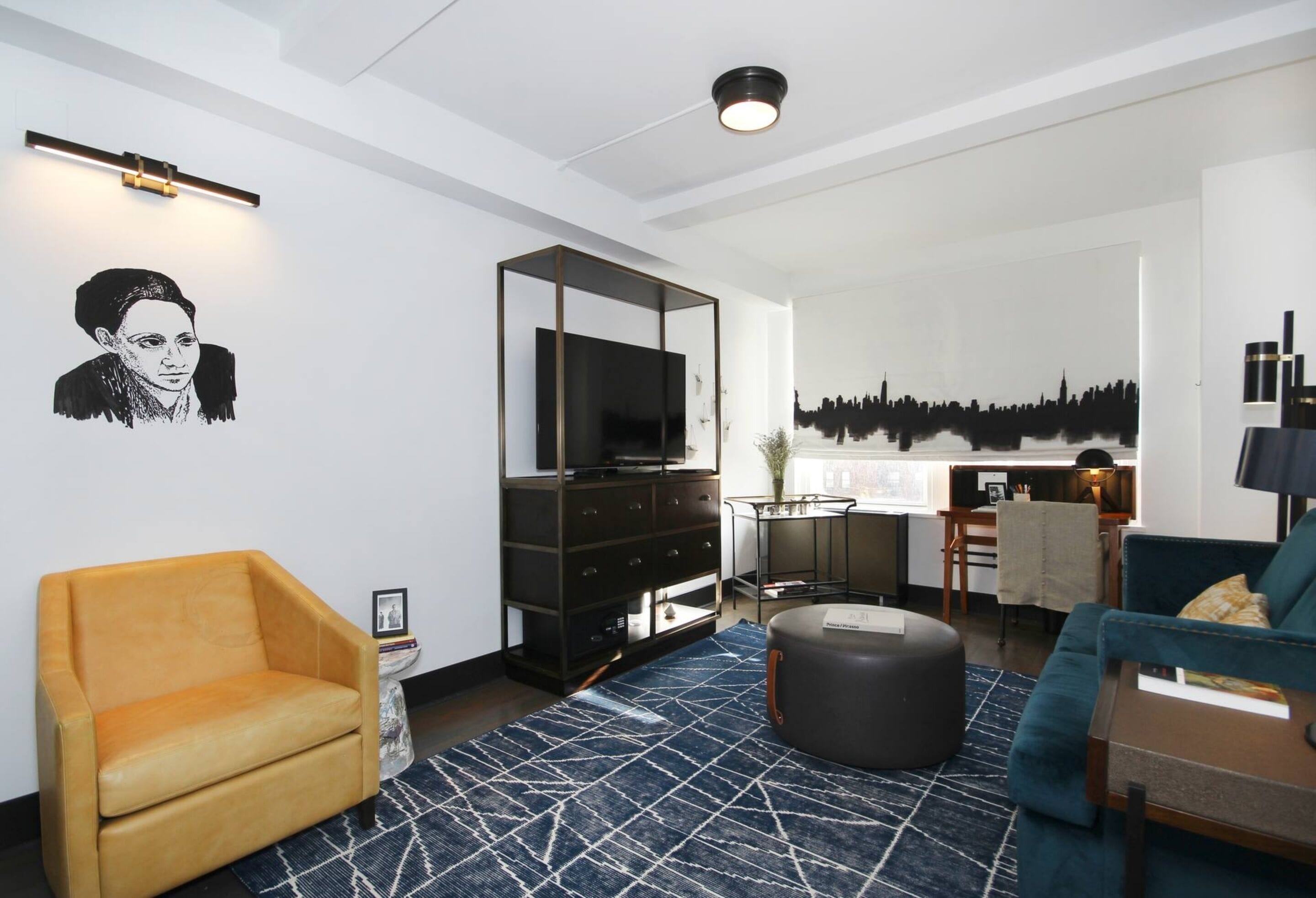 A modern living room with a sofa, ottoman, and a TV on a black cabinet.