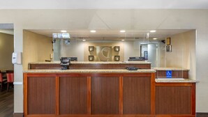 A reception desk with a wooden finish, a digital payment terminal, and a wheelchair accessibility sign. - Comfort Inn Edison - New Brunswick (Edison)