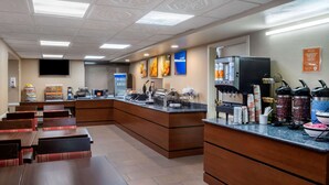 A restaurant with a counter, seating area, and various amenities like a coffee machine and condiment dispensers. - Comfort Inn Edison - New Brunswick (Edison)