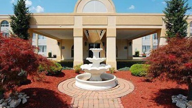 A building with a central fountain, surrounded by red foliage and a brick pathway. - Comfort Inn Edison - New Brunswick (Edison)