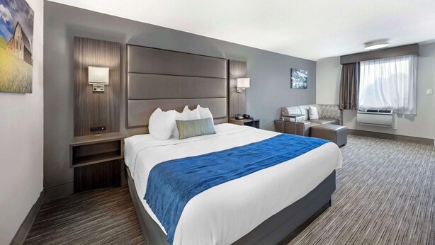 A hotel room with a large bed, a desk, a chair, a flat-screen TV, and a window with curtains.