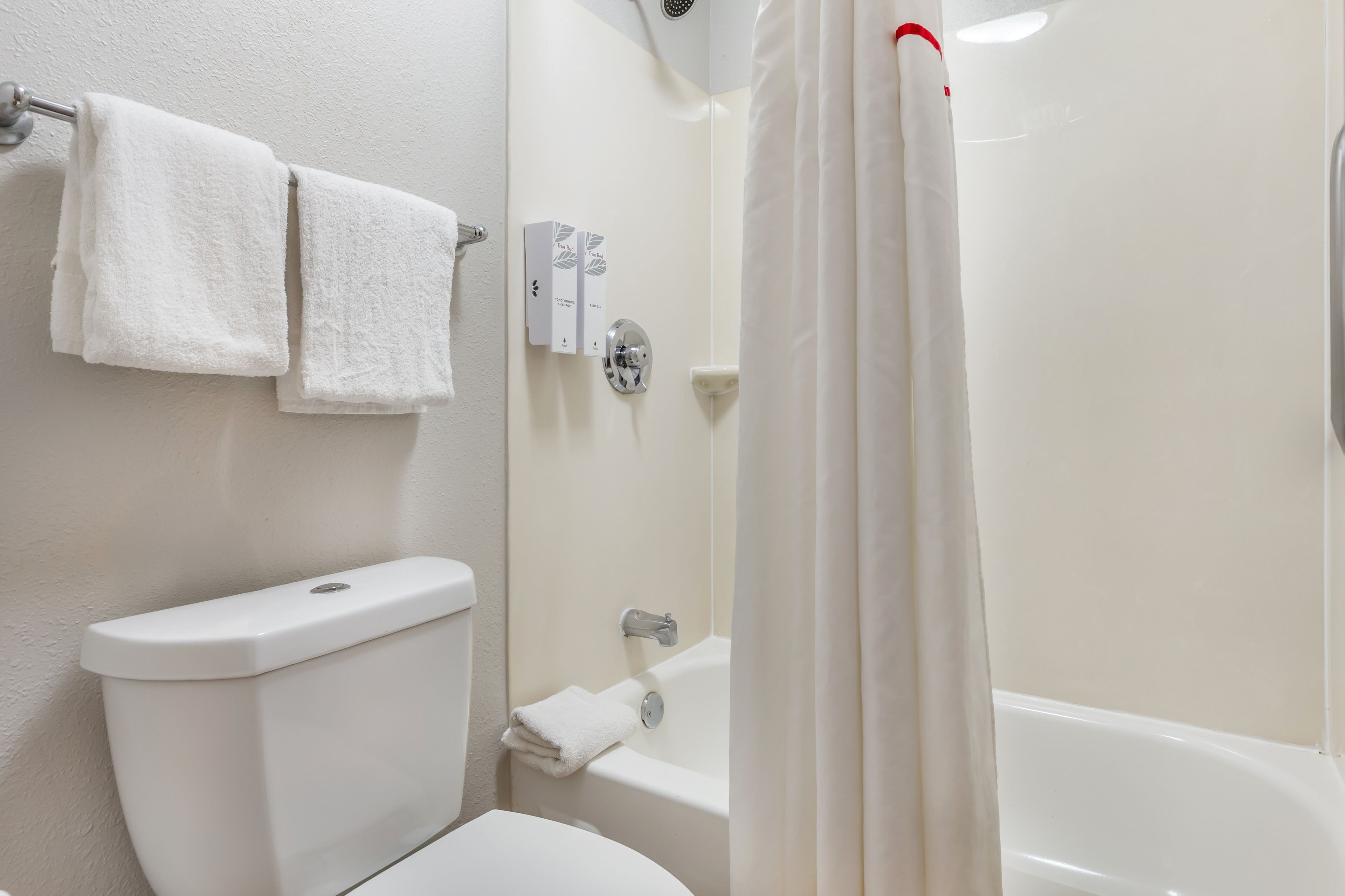 Une salle de bain équipée de toilettes, d’une baignoire et d’un rideau de douche.