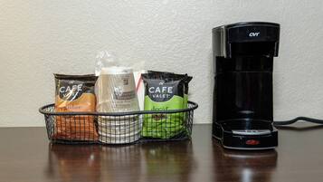 A coffee maker and a basket with coffee pods on a table.