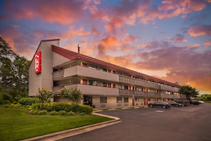 A motel with a red and white sign, multiple balconies, and a parking lot. - Red Roof Inn Durham - Duke Univ Medical Center (Durham)