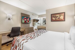 A hotel room with a bed, a desk, a chair, a television, a mirror, and a framed picture on the wall. - Red Roof Inn Durham - Duke Univ Medical Center (Durham)