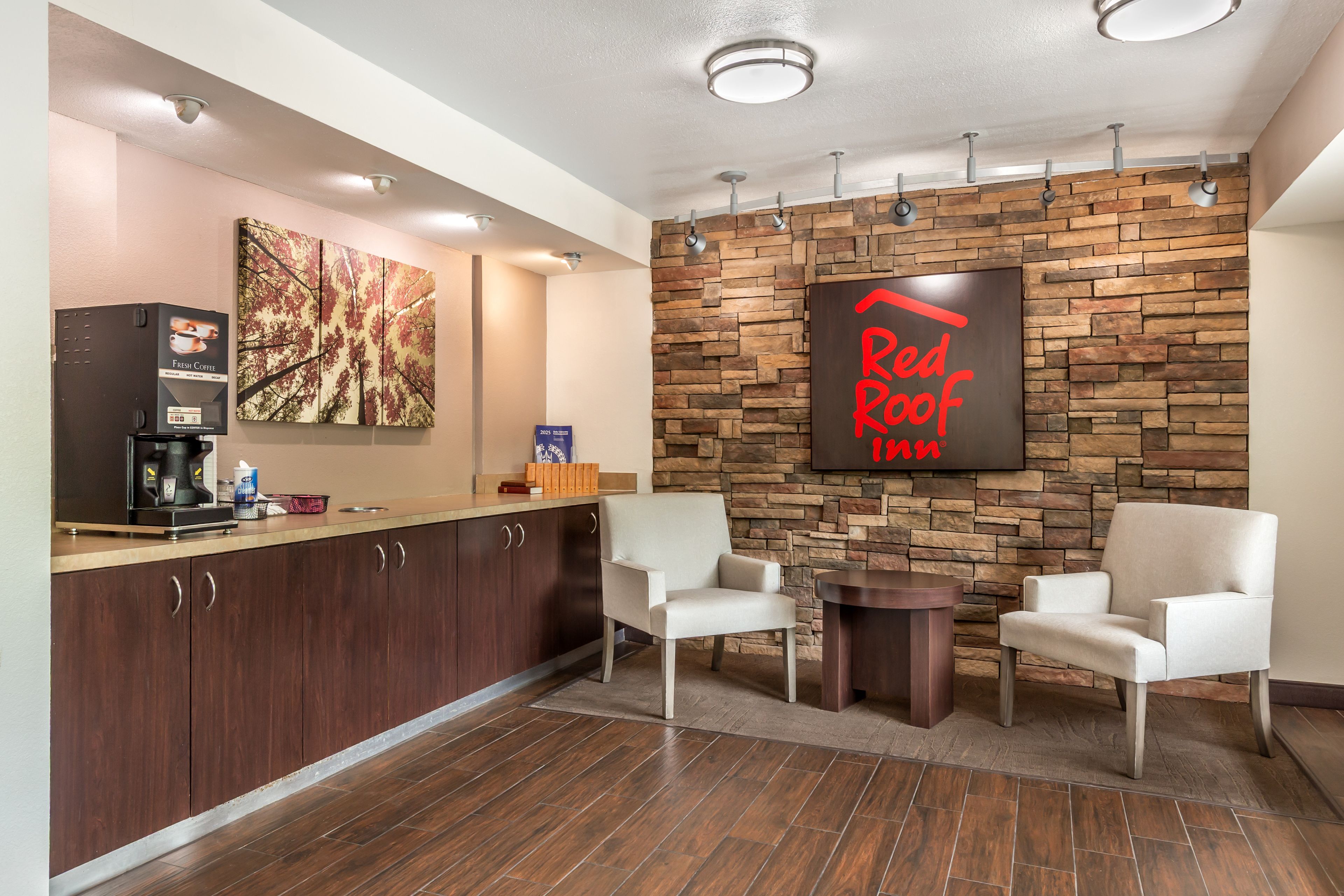 A Red Roof Cafe with a stone wall, a coffee machine, and two white chairs.