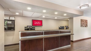A reception area with a digital screen displaying "Free Wi-Fi All Rooms," a self-service kiosk, and a counter with a telephone. - Red Roof Inn Durham - Duke Univ Medical Center (Durham)