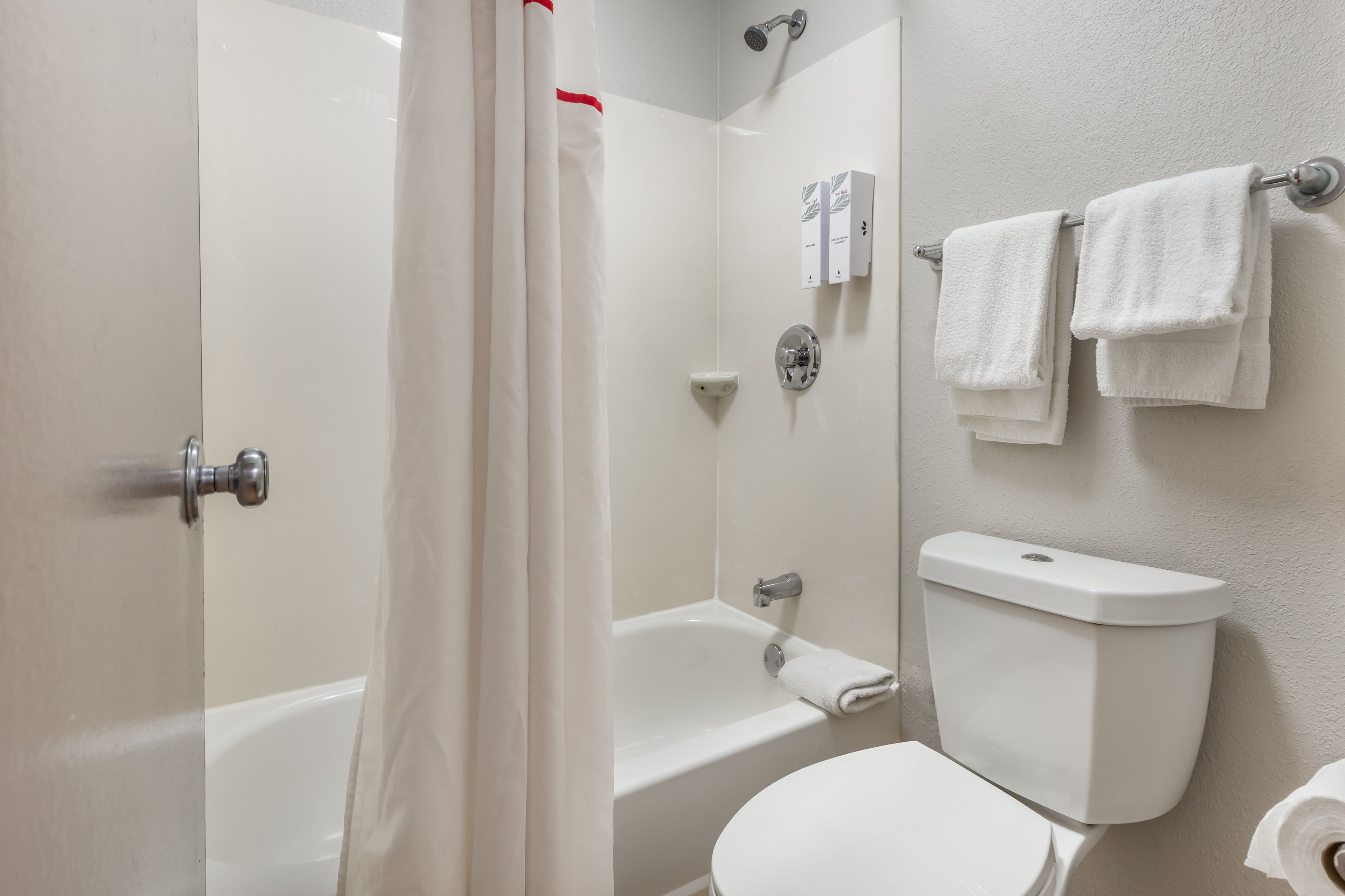 A bathroom with a bathtub, toilet, and a shower curtain.