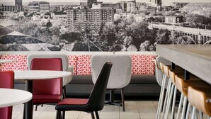 A restaurant with a cityscape mural, red and grey chairs, and a bar area. - Ramada by Wyndham Allentown/Bethlehem (Whitehall)