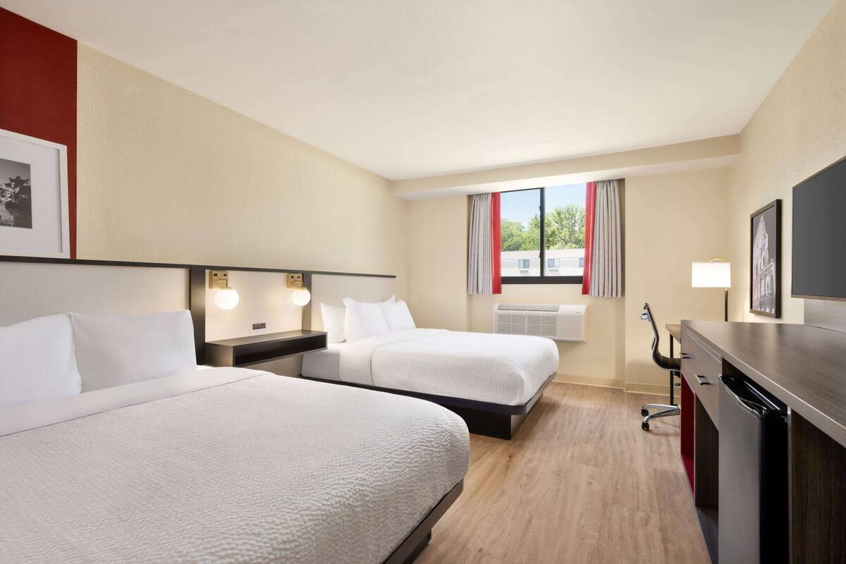 Een hotelkamer met twee bedden, een bureau, een stoel en een televisie.