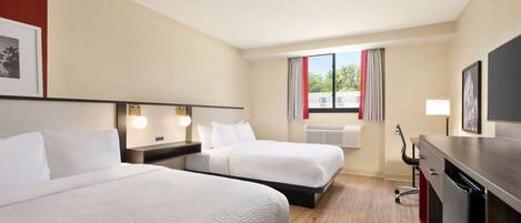 A hotel room with two beds, a desk, a chair, and a television.