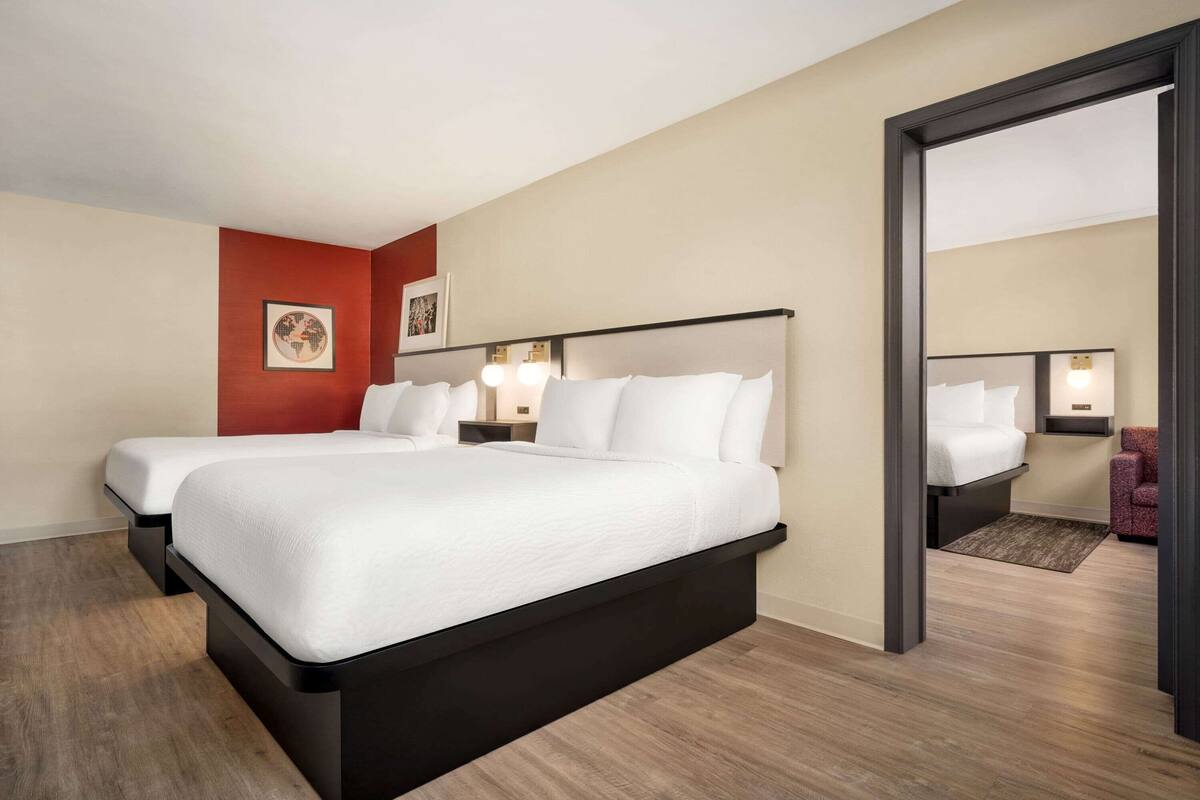Een hotelkamer met twee bedden, een rode accentmuur en een grote spiegel.