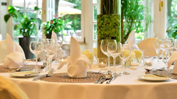 Une table dressée pour un repas formel, avec de beaux verres, des serviettes blanches et un vase décoratif.