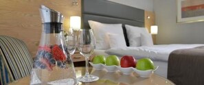 A hotel room with a bed, a bedside table with a fruit bowl, a glass of water, and a bottle. - Best Western Hotel Der Foehrenhof (Hannover)