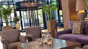 A lobby with seating, a reception desk, and a large window with a view of the street. - Best Western Hotel Der Foehrenhof (Hannover)
