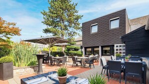 An outdoor dining area with tables and chairs, surrounded by potted plants and a pergola. - Best Western Hotel Der Foehrenhof (Hannover)