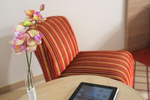 A tablet on a round table with a vase of orchids. - Best Western Hotel Der Foehrenhof (Hannover)