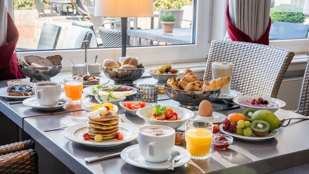 A breakfast table with various food items, a cup of coffee, and a glass of orange juice. - Best Western Hotel Der Foehrenhof (Hannover)