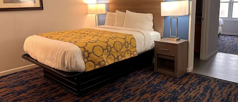 A neatly made bed with a patterned bedspread, two bedside lamps, and a wooden nightstand.