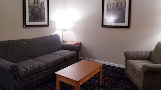 Een hotelkamer met een gestreepte bank, een houten bijzettafeltje en twee ingelijste foto's aan de wand.