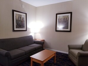 Une chambre d’hôtel avec un canapé à rayures, une table basse en bois et deux tableaux encadrés accrochés aux murs.