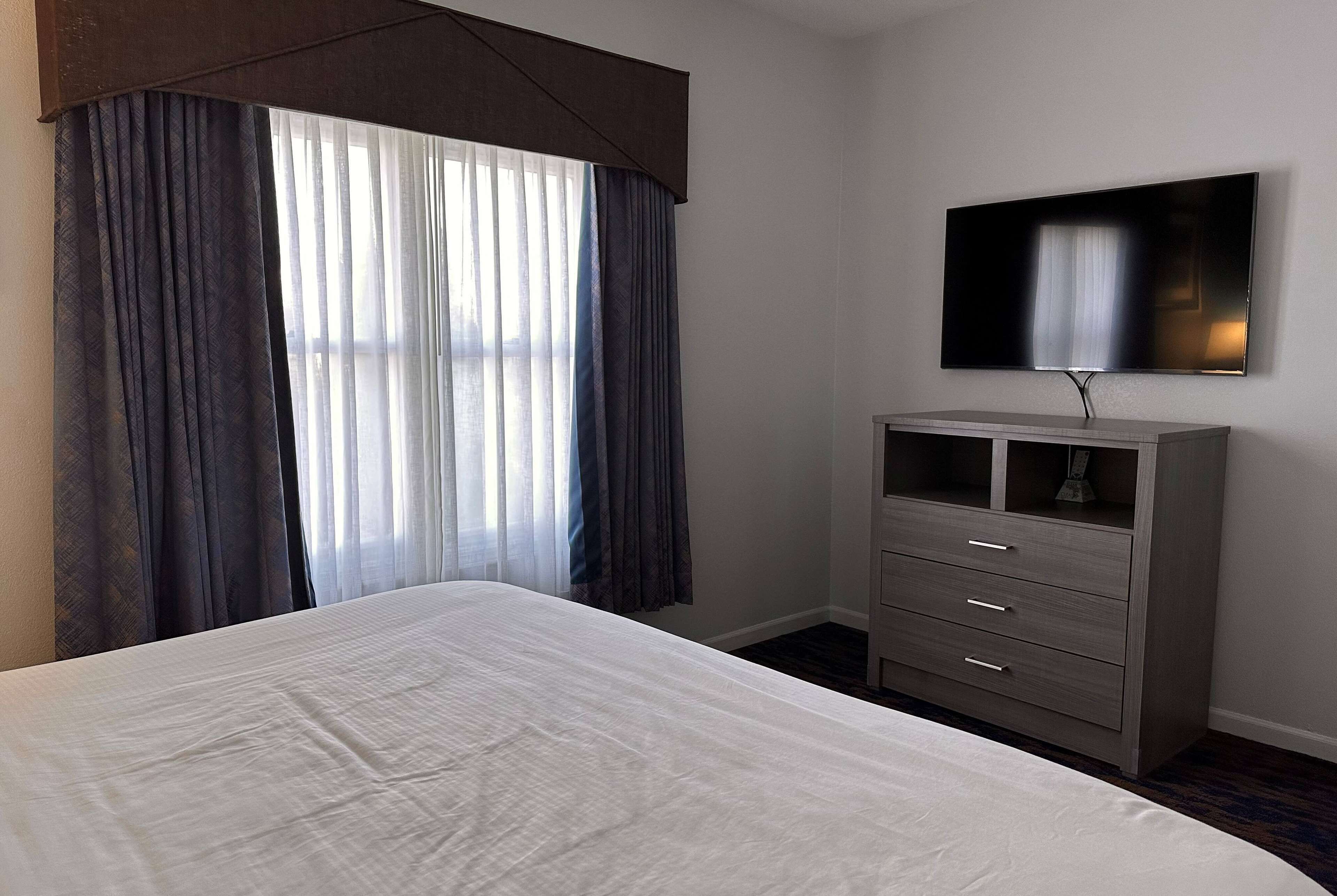 Una habitación de hotel con una cama, un televisor montado en la pared y un aparador.