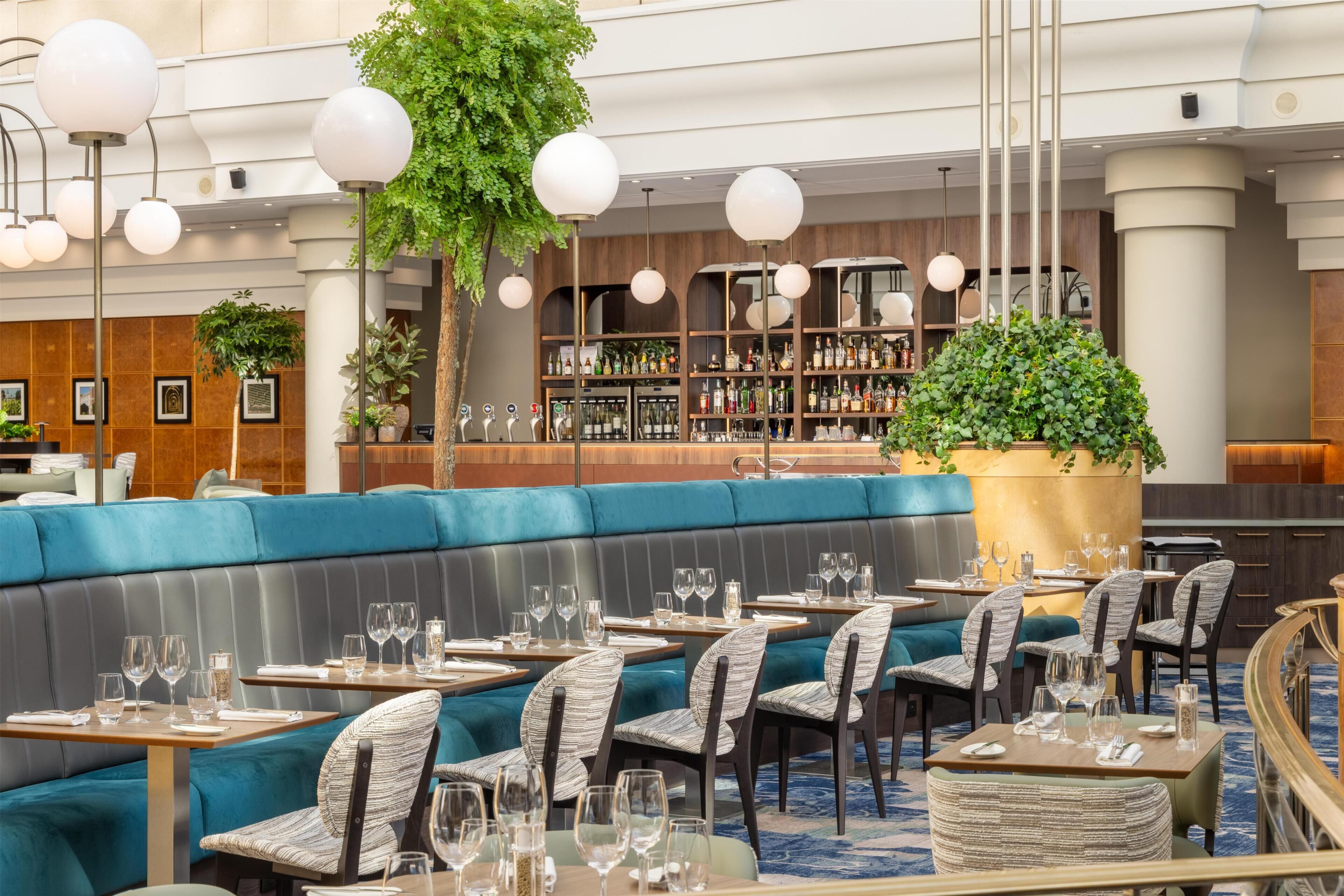 A restaurant with a bar area, seating arrangements, and a variety of bottles on shelves.