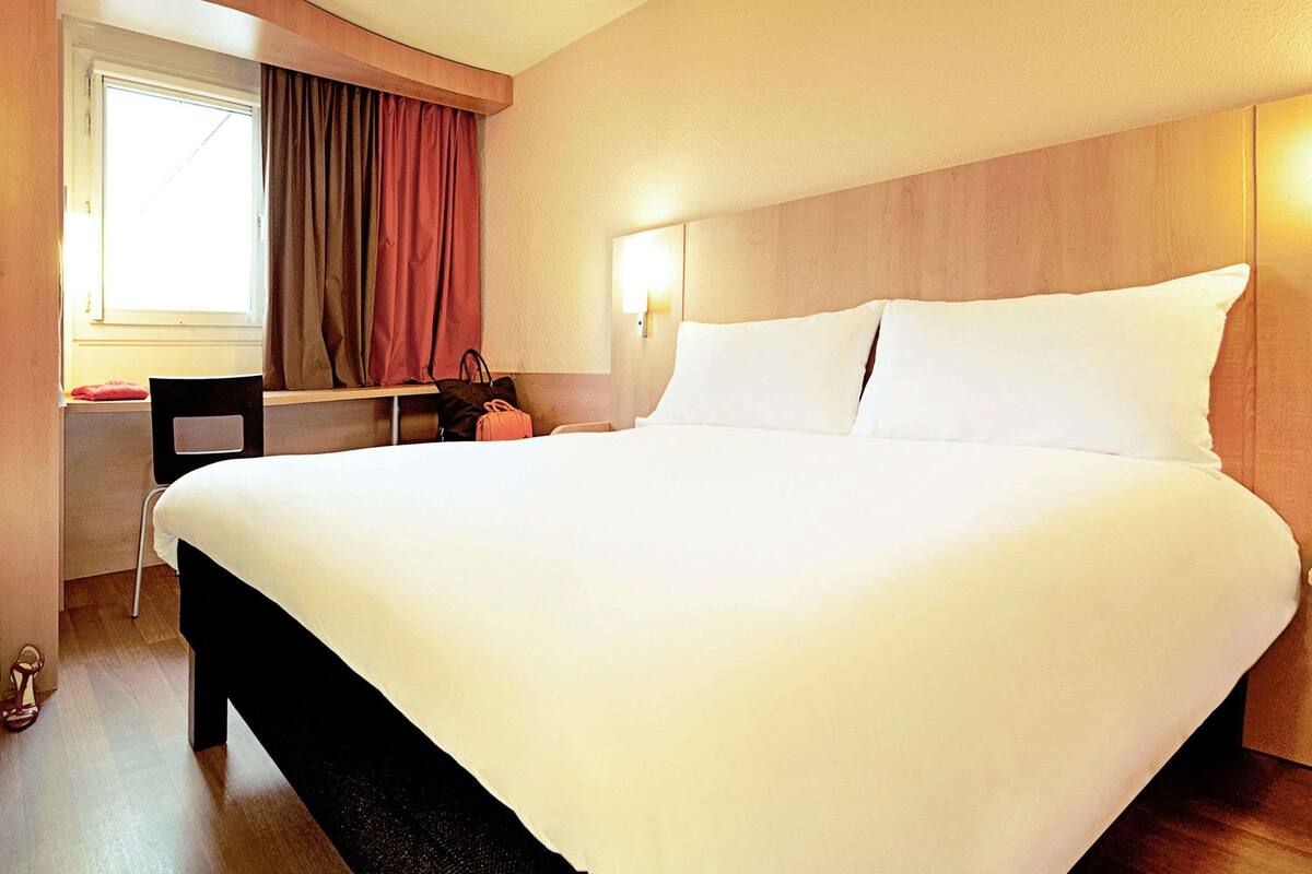 Una habitación de hotel con una cama grande, un escritorio y una silla.