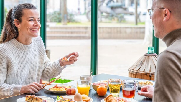Une table à manger avec des aliments pour le petit-déjeuner, un verre de jus d’orange et une bouteille d’eau.