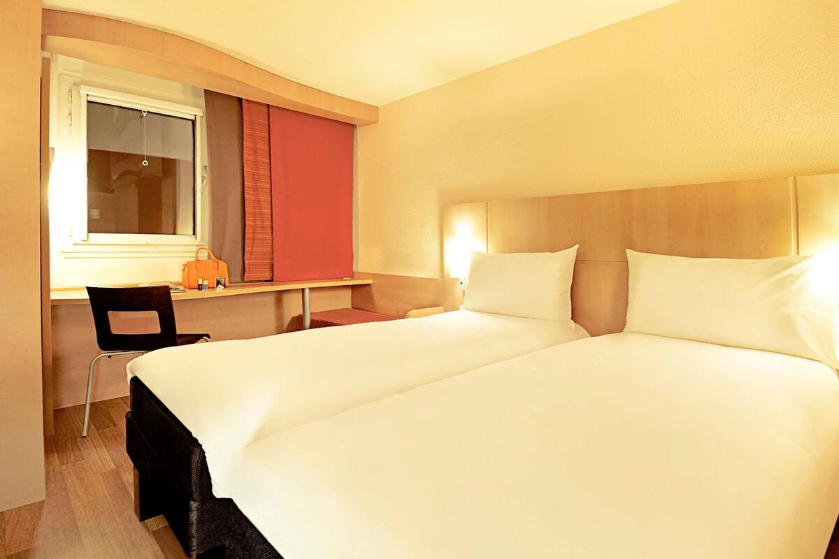 Una habitación de hotel con cama, escritorio, silla y ventana.