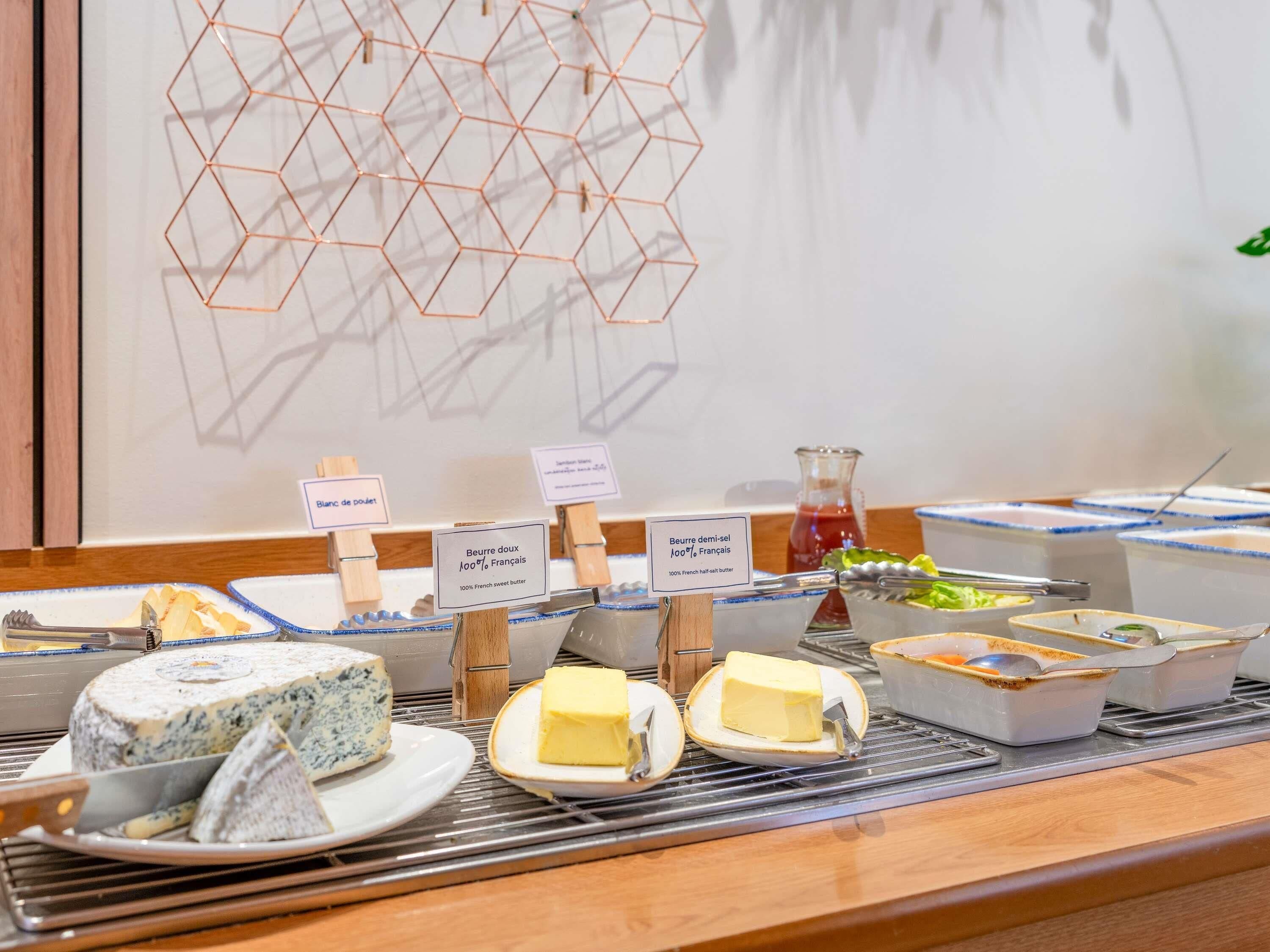 Un bufé con diversos quesos y untables, incluyendo queso azul y mantequilla francesa dulce.