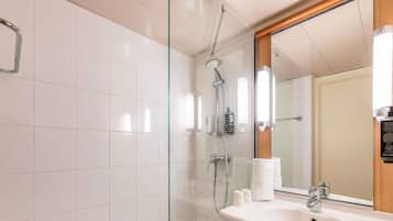 Un baño moderno con cabina de ducha de vidrio, un lavabo blanco y un espejo grande.