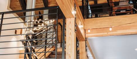 Interior de madera de varios niveles, con escalera, ventilador de techo y luz natural proveniente de ventanas.