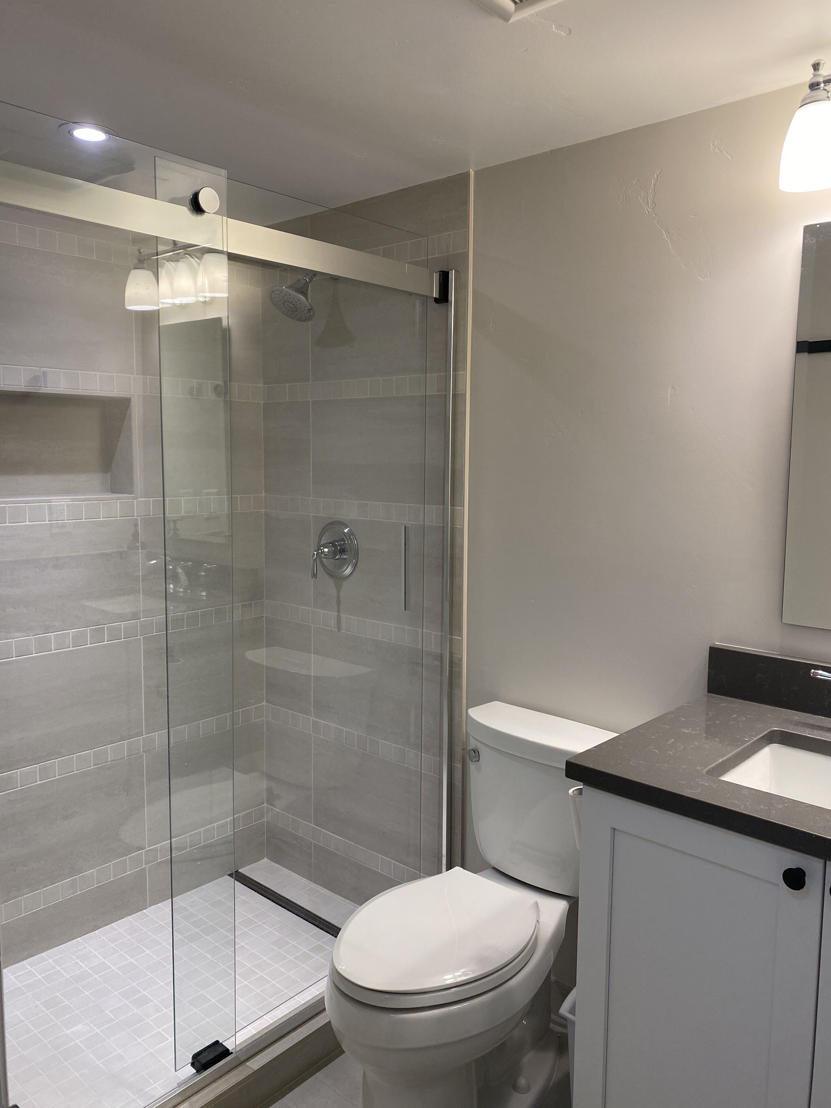 Ein modernes Badezimmer mit einer Duschkabine, einer weißen Toilette und einem Waschtisch.