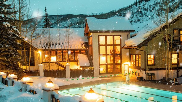 A hotel with a swimming pool surrounded by snow-covered trees and a mountain backdrop. - Vail Racquet Club Mountain Resort (Vail)