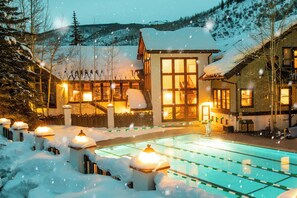 A hotel with a swimming pool surrounded by snow-covered trees and a mountain backdrop. - Vail Racquet Club Mountain Resort (Vail)