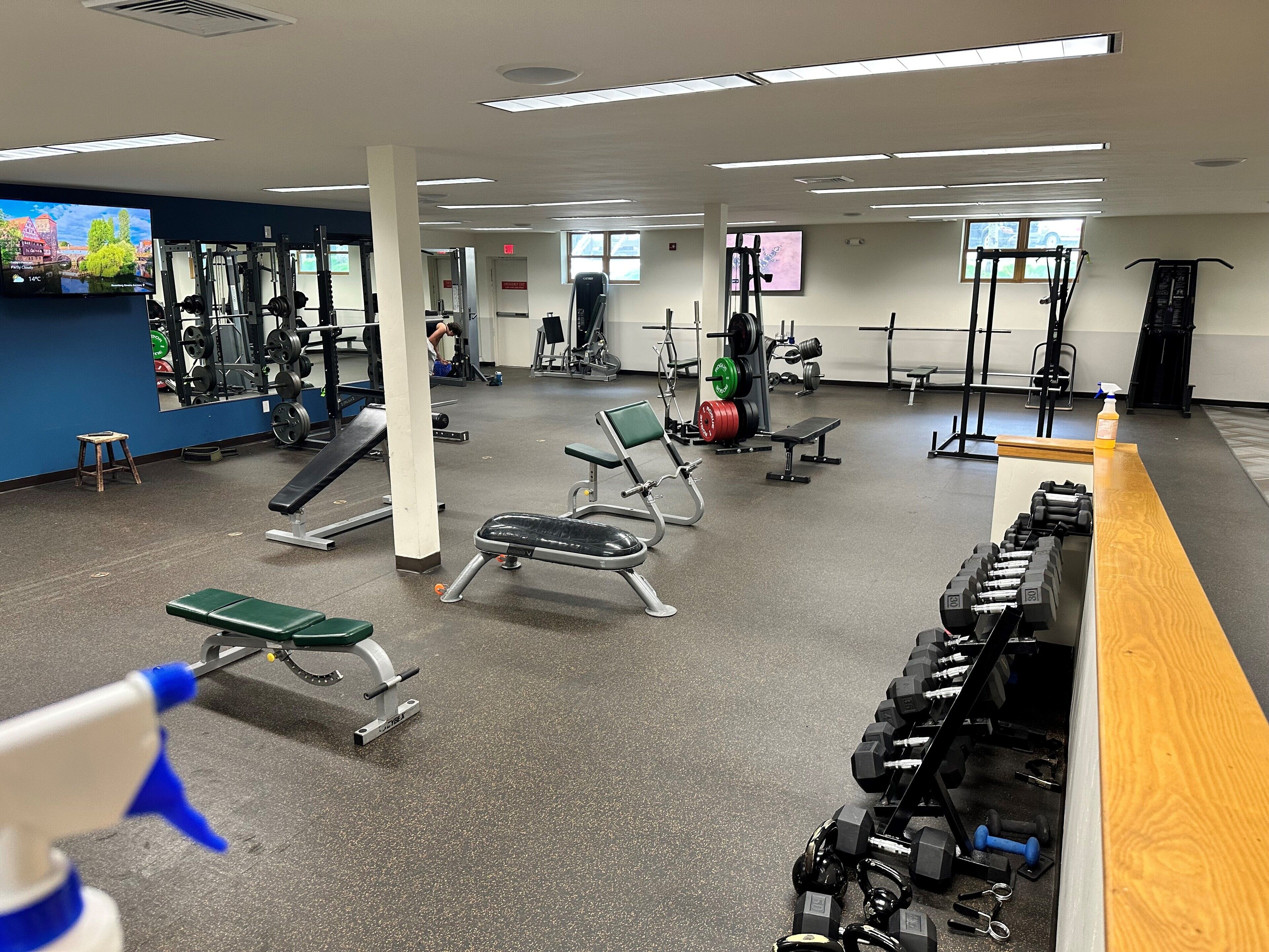 Uma academia com diversos equipamentos de exercícios, incluindo bancos, halteres e aparelhos de musculação.