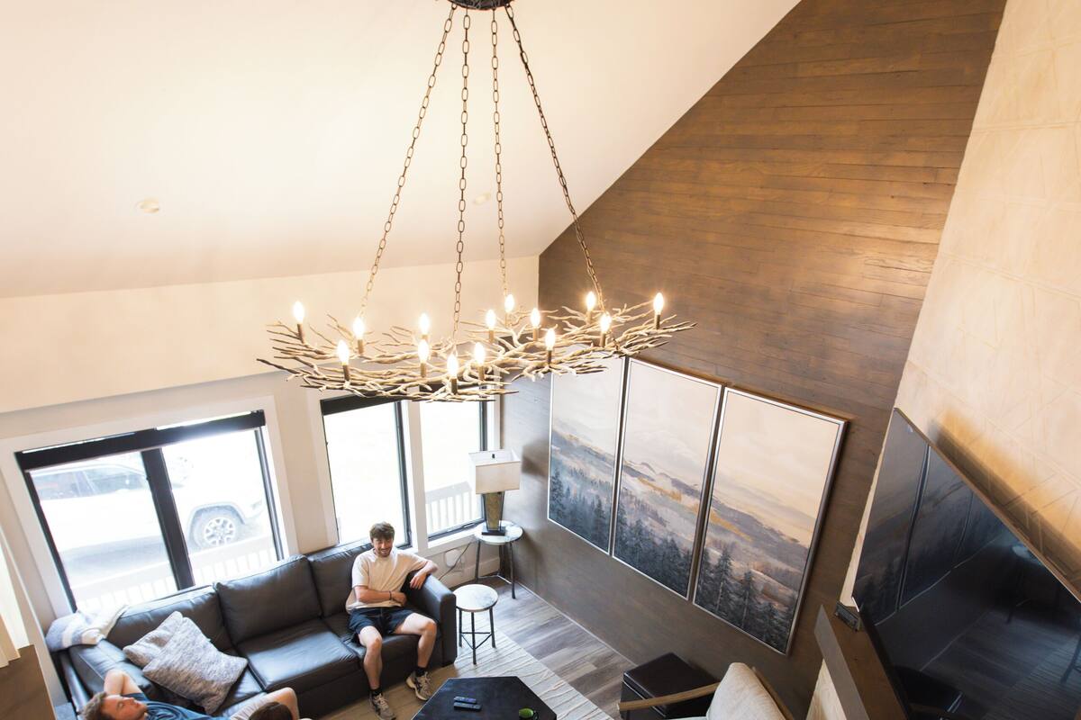 Un salon moderne doté d’un grand canapé d’angle, d’une cheminée et offrant une vue sur l’extérieur.