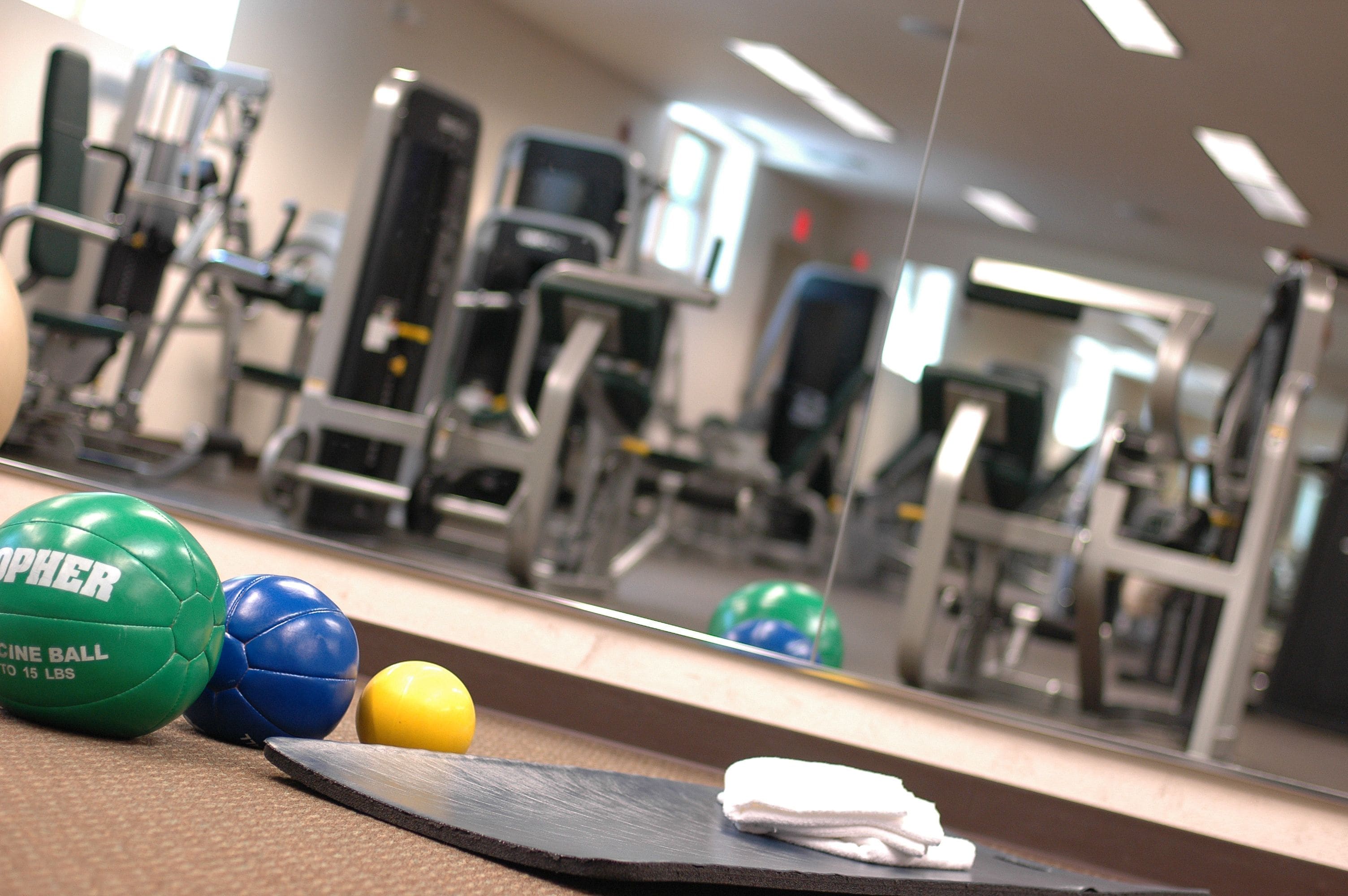 Gym equipment, exercise balls, and a towel on a mat.