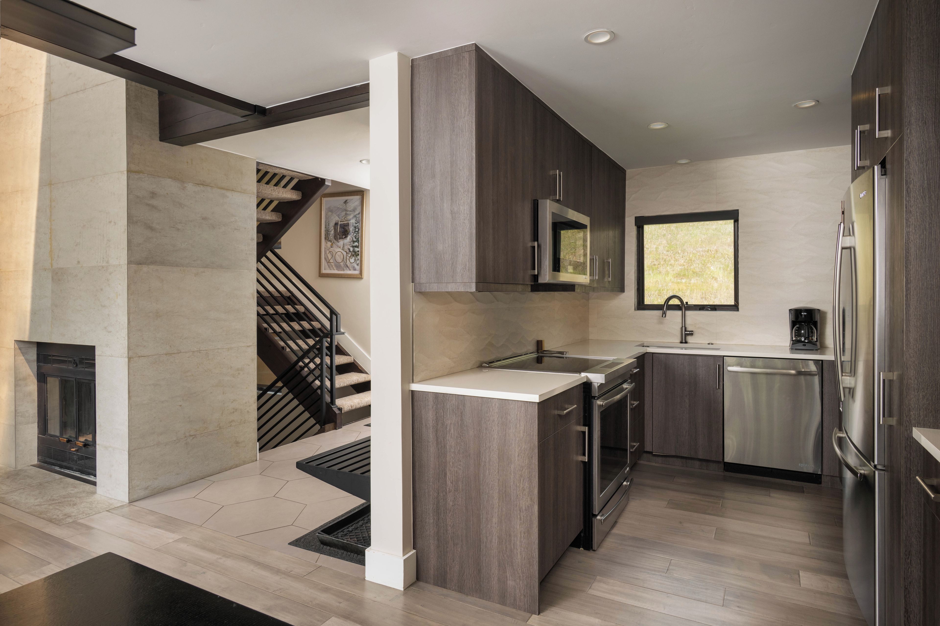 A modern kitchen with a built-in microwave, stainless steel appliances, and a window.